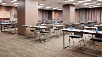 A conference room with multiple tables, chairs, and water bottles.