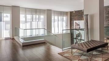 A spacious living area with a glass railing, a cushioned bench, and a patterned rug.