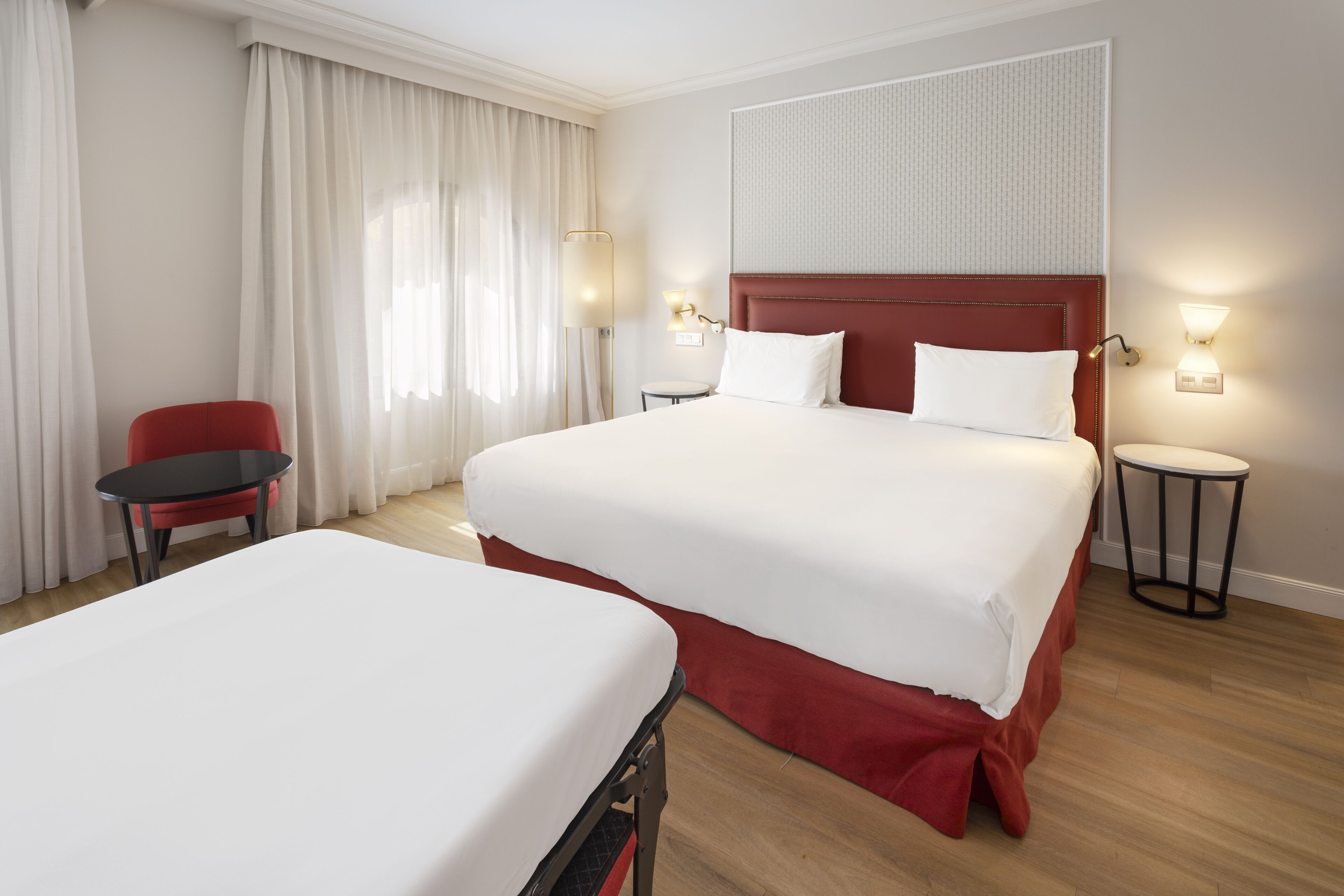Ett hotellrum med två sängar, en röd stol, ett litet bord och två sänglampor.