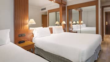 A hotel room with a large bed, bedside tables, a mirror, and a wardrobe.
