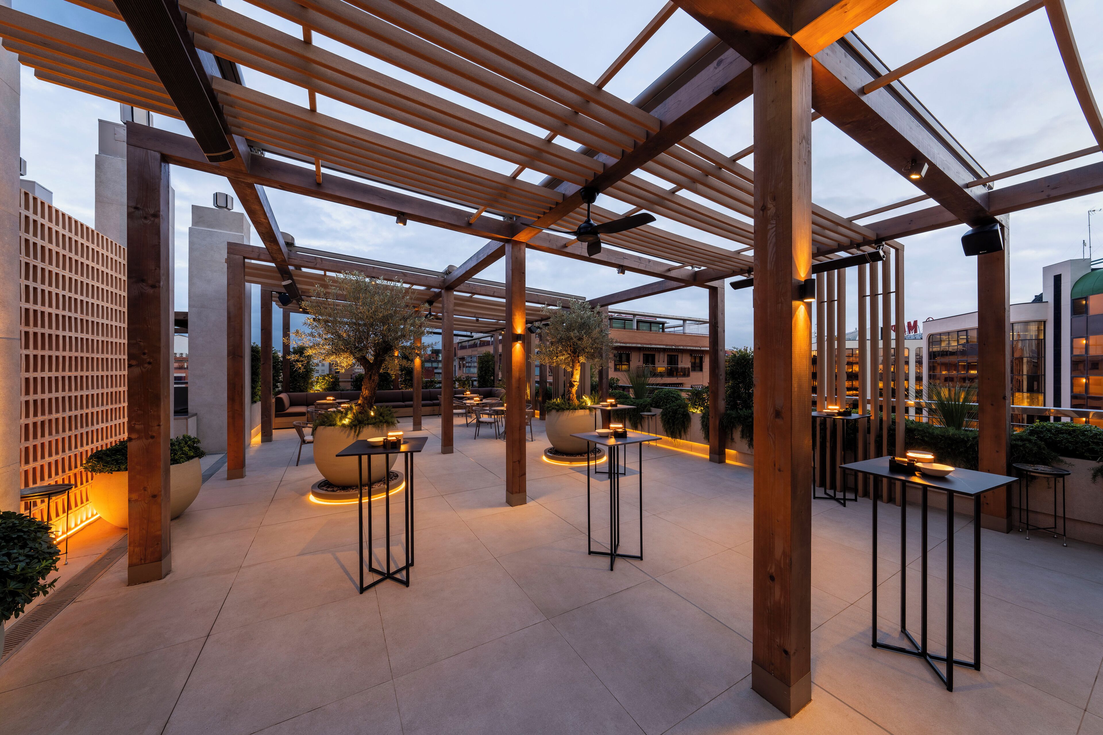 Een terras met houten pergola’s, zitgedeeltes en tafels.