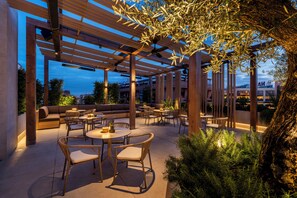 An outdoor patio area with wooden pergolas, seating, and tables. - SH Valencia Palace Hotel (Valencia)