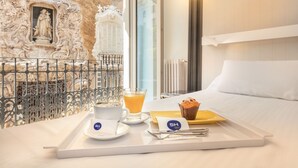 Une chambre d’hôtel avec un lit, un plateau contenant des articles pour le petit-déjeuner, une statue et un mur décoratif.