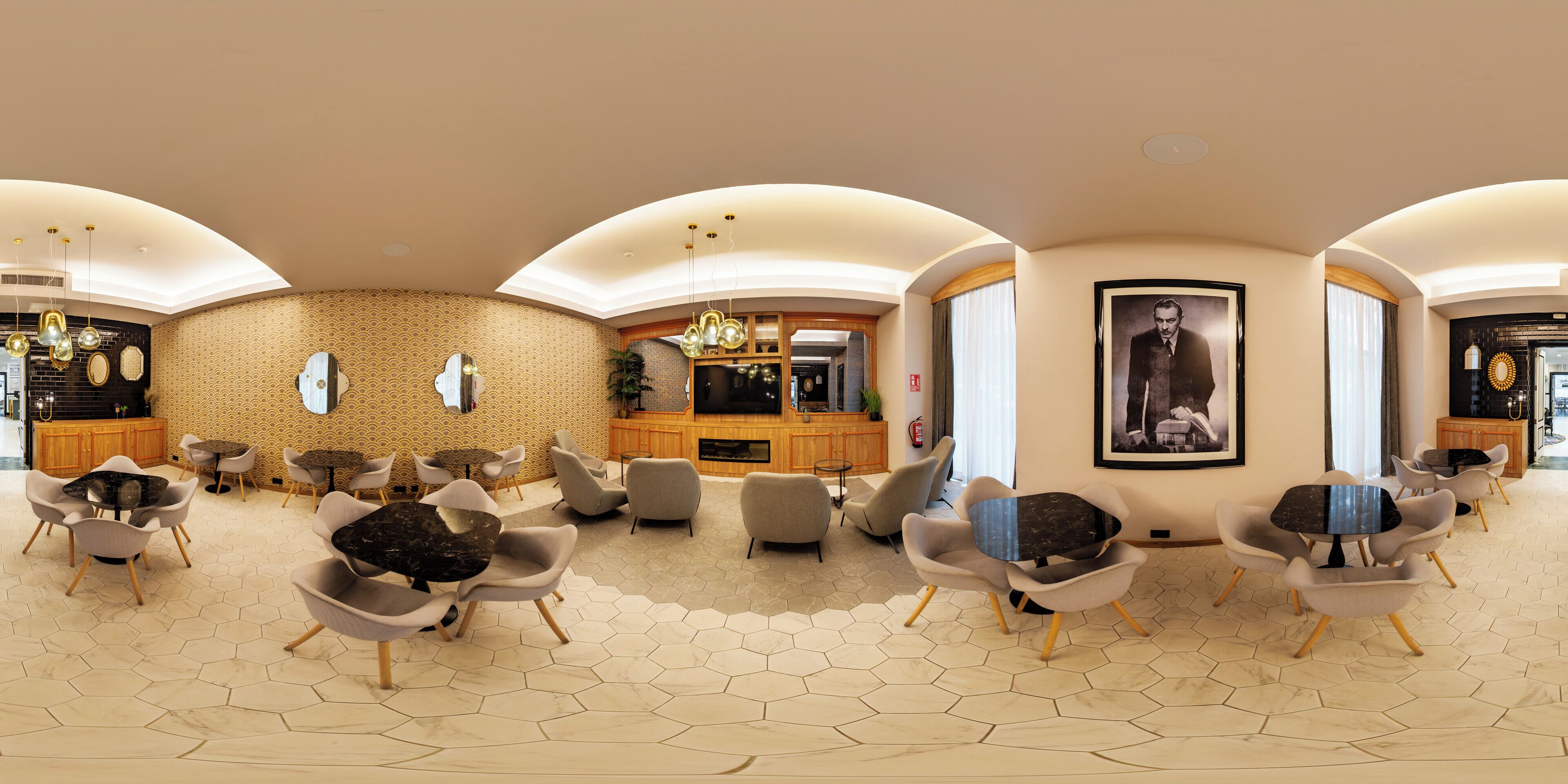 Eine geräumige Lobby mit sechseckigem Fußbodenmuster, modernen Möbeln und einer zentralen Sitzecke mit einem großen, an der Wand montierten Fernseher.