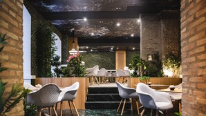 Un espace de restauration intérieur moderne, doté d’un haut plafond, de murs en briques apparentes et d’un décor de plafond représentant un ciel étoilé. Plusieurs chaises et tables blanches sont disposées pour accueillir les convives.