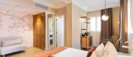A hotel room with a bed, a sofa, a desk, and a dining area.