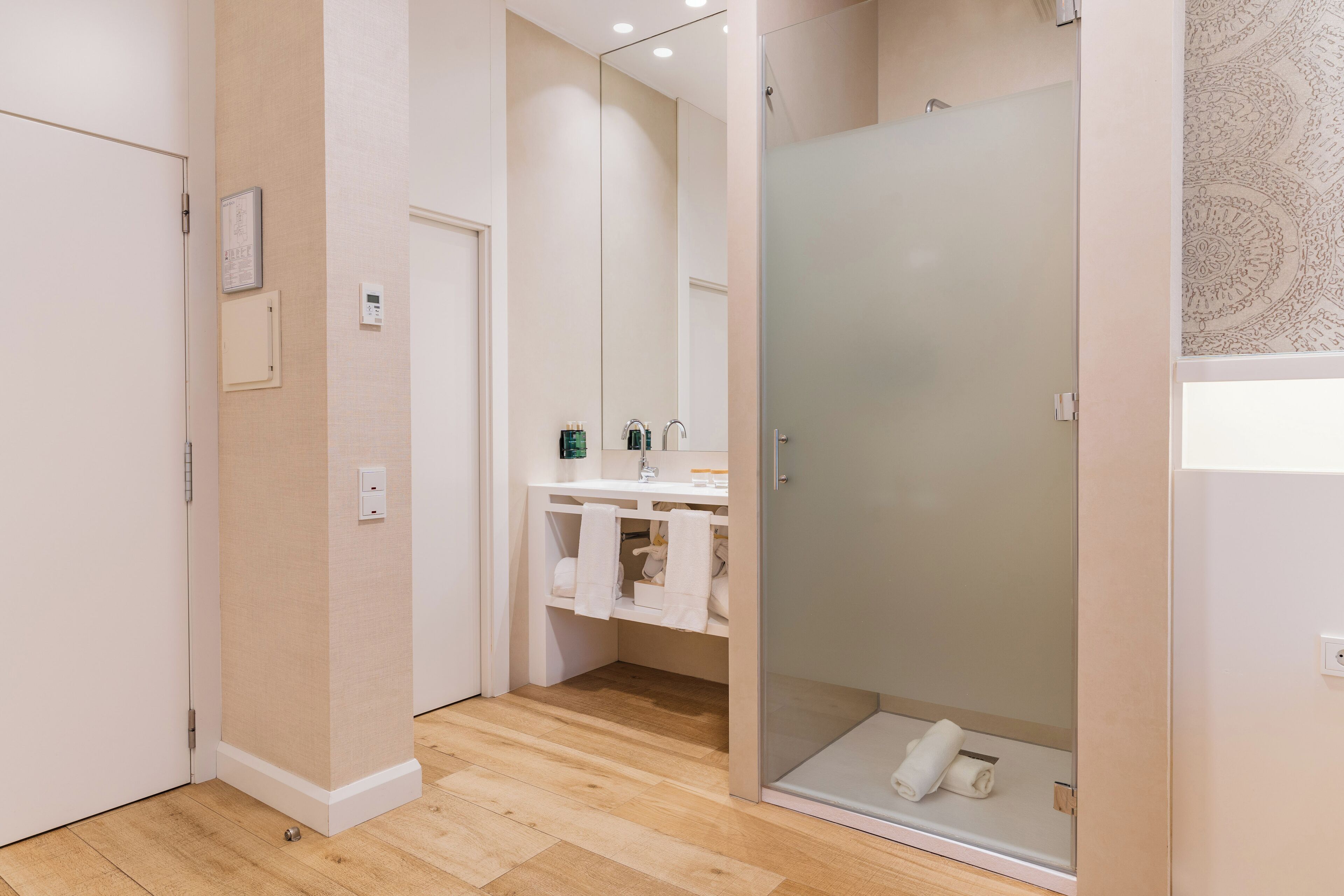 Un baño moderno con cabina de ducha de vidrio, un espejo y tocador con lavabo y perchero para toallas.