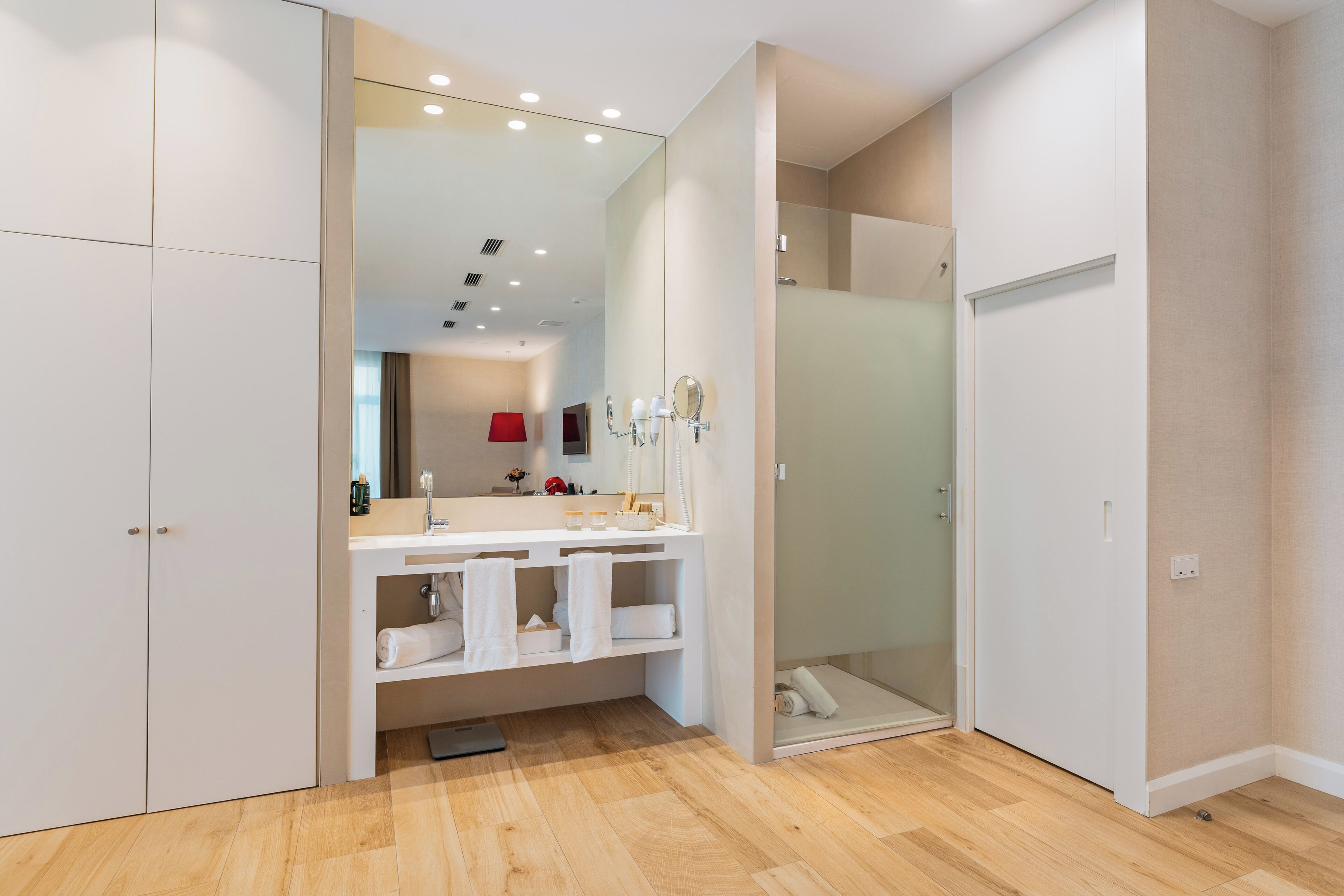 Un baño moderno con un espejo grande, ducha y tocador con toallas.