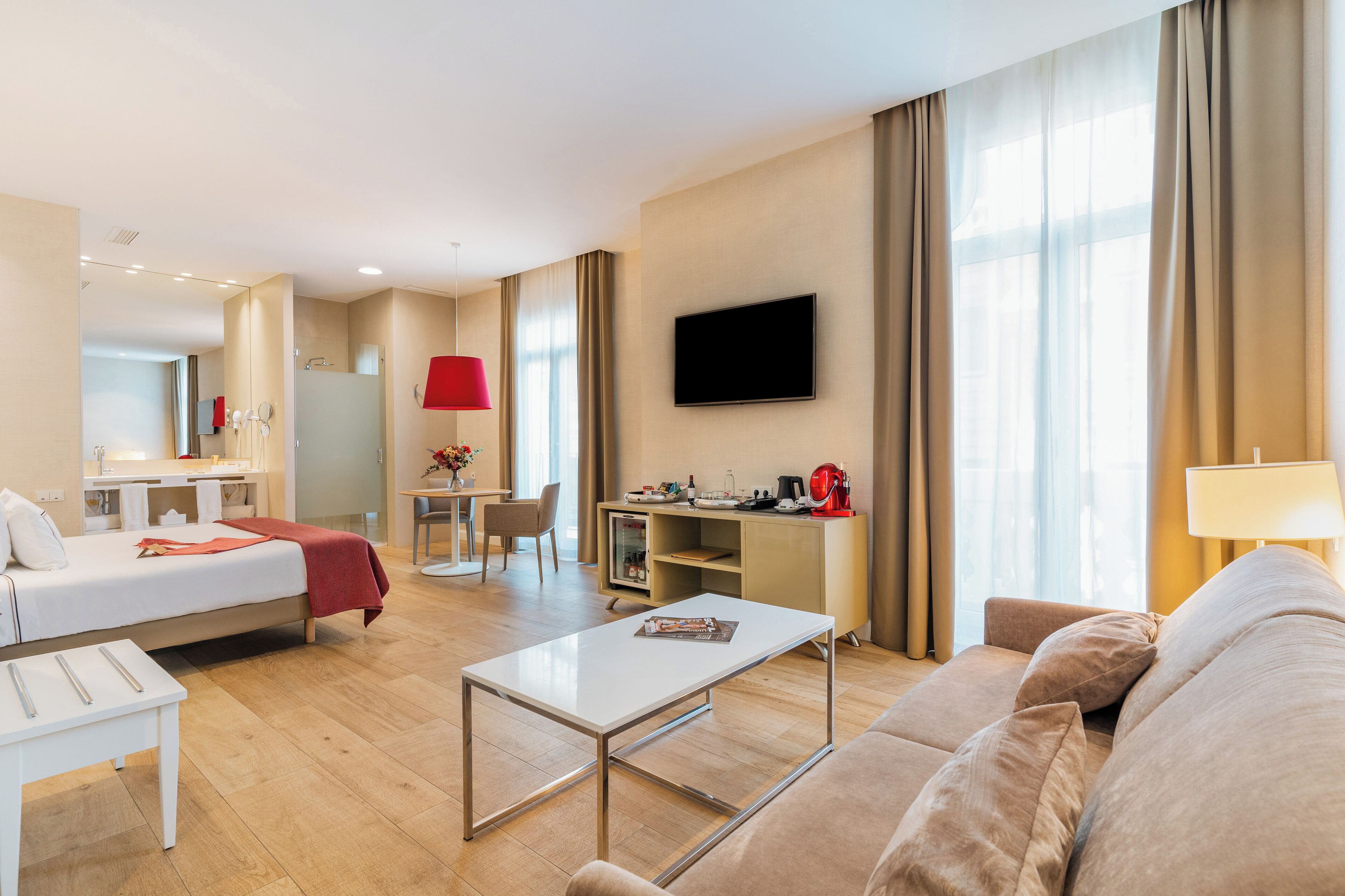 Ein modernes Hotelzimmer mit Bett, Schreibtisch, Fernseher und einer Sitzecke.