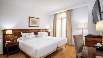 Habitación de hotel con una cama doble, un escritorio con silla, televisión y un cuadro en la pared.