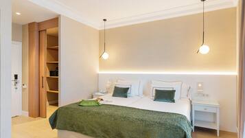 Una habitación de hotel moderna con una cama grande, mesitas de noche, un armario y una lámpara en el techo.