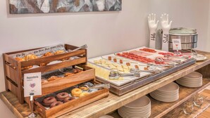 Un bufé de desayuno con bollería, quesos y embutidos.