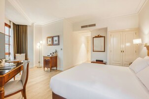 Una camera d'albergo con un letto, una scrivania, una sedia, un armadio e uno specchio.