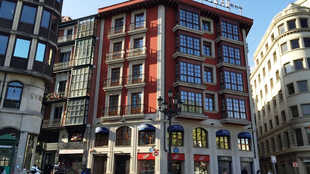 Un hotel de varios pisos con balcones, fachada roja y letreros que indican 'Arenal Hotel'.