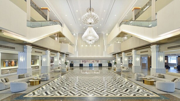 Um hall amplo com piso de padrão geométrico, iluminação moderna e um lustre central.