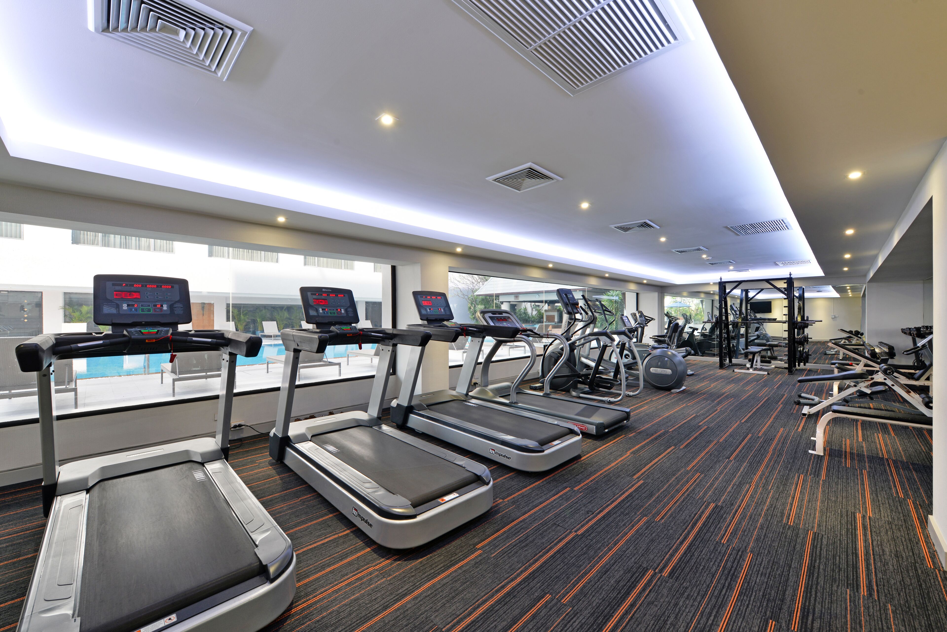 Une salle de sport équipée de tapis de course, de vélos d’exercice et d’appareils de musculation.