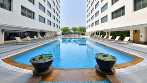Piscina com cadeiras de descanso e um elemento aquático no centro.