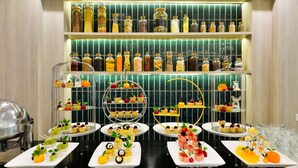 Uma mesa de buffet com diversos alimentos e garrafas de temperos.
