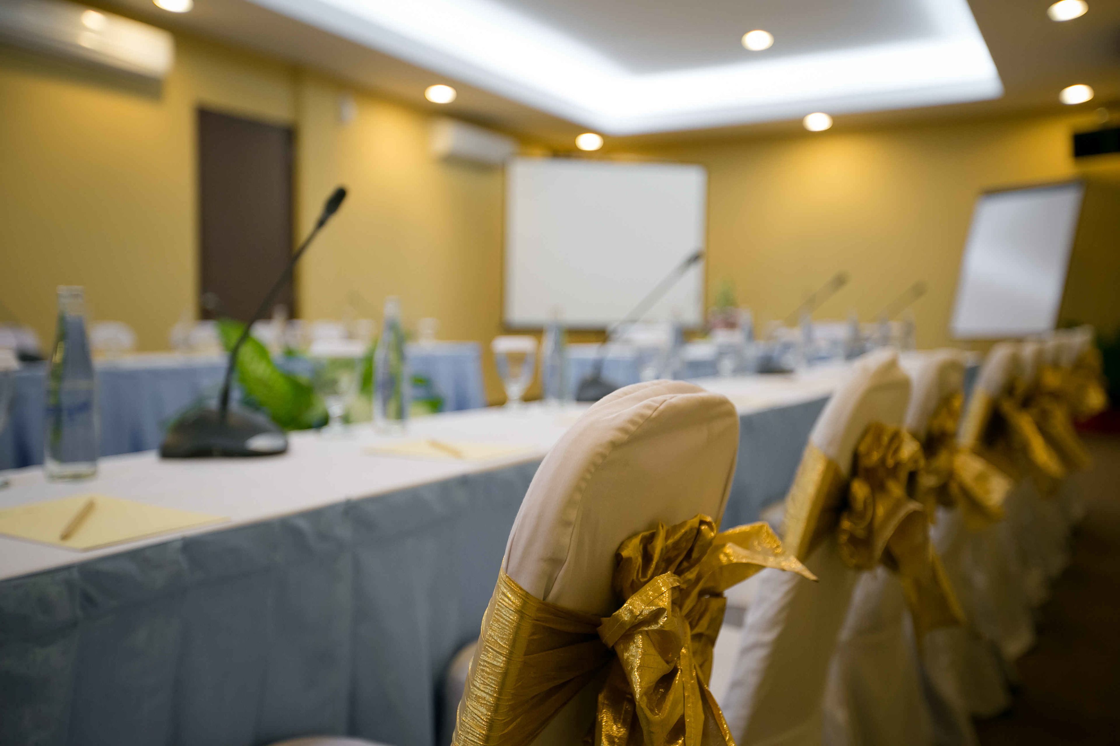 A conference room with rows of chairs, a whiteboard, and a projection screen.