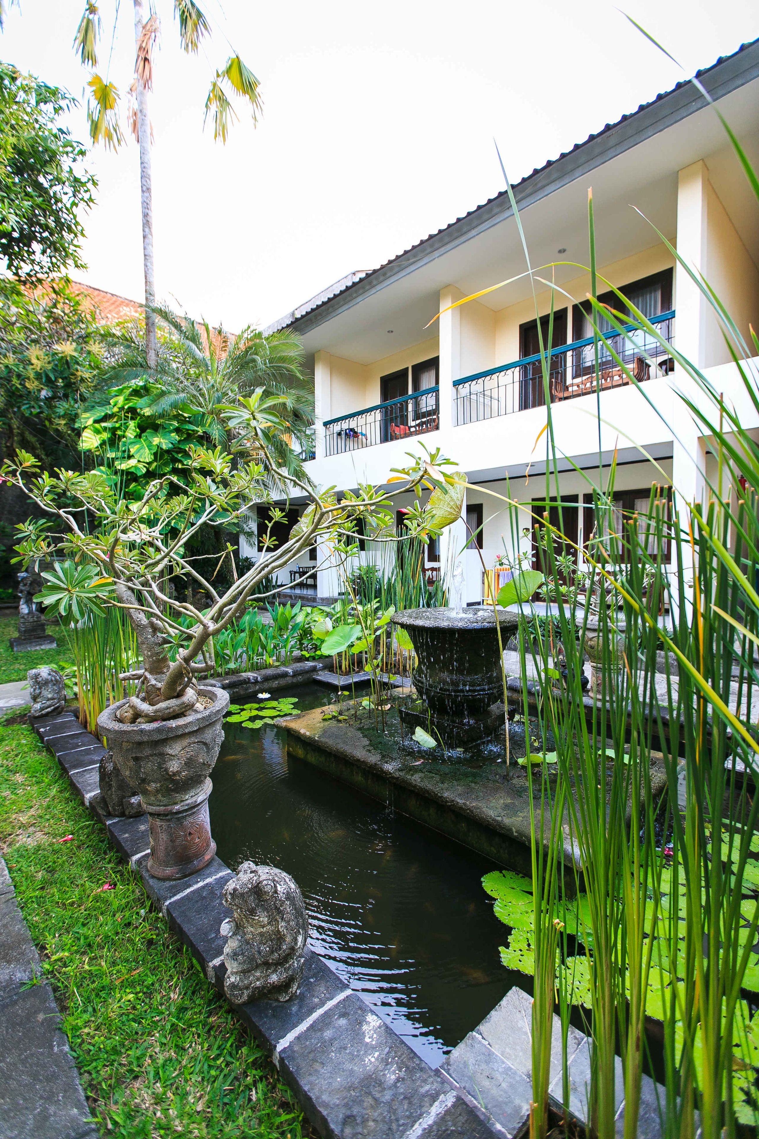 A courtyard with a small pond, stone statues, and lush greenery.