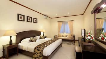Habitación de hotel con una cama grande, un sofá, un escritorio y un espejo.