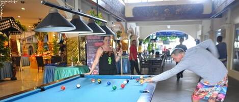Una mesa de billar en un espacio interior público, con una persona inclinándose sobre ella.