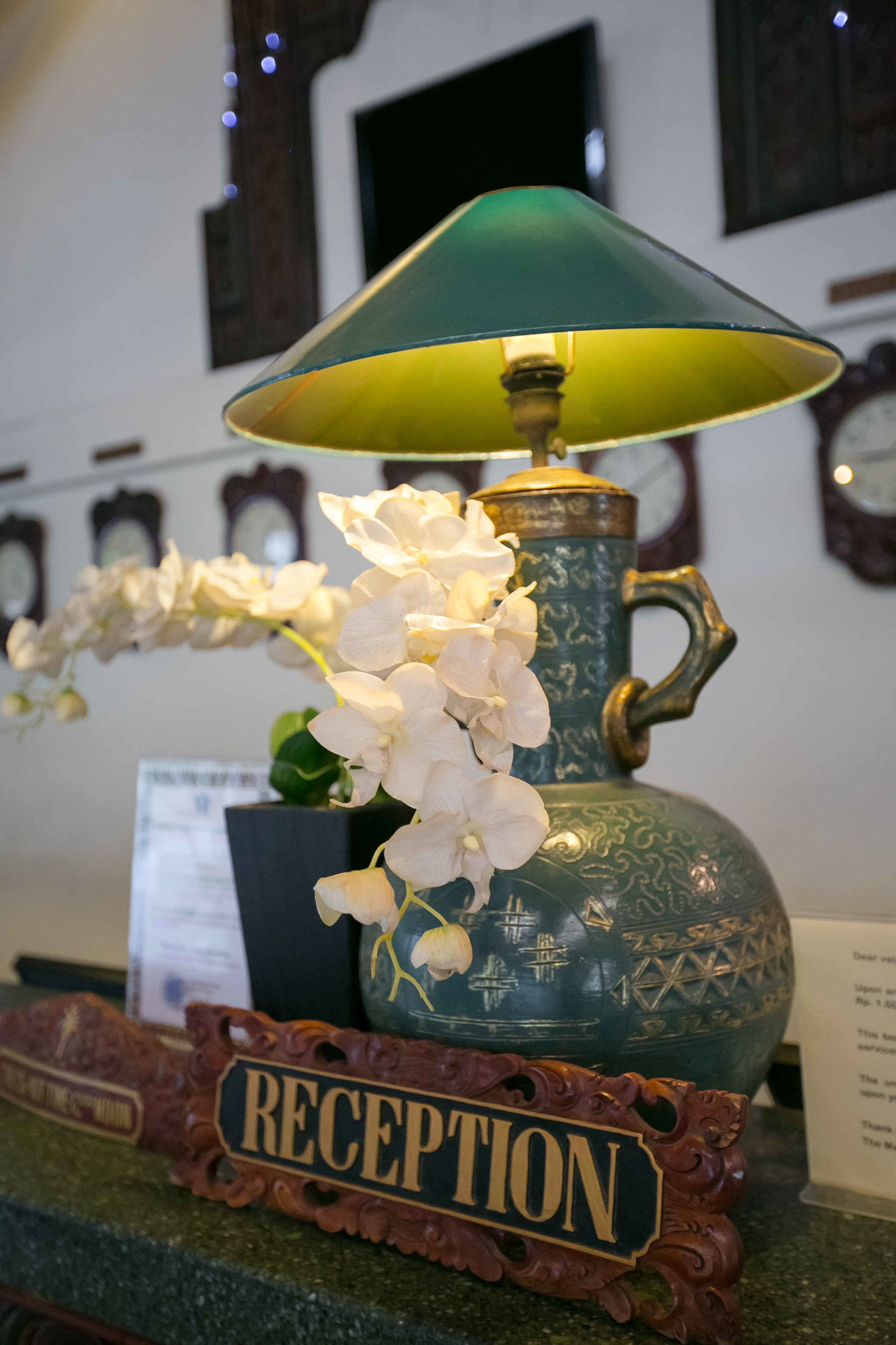 A reception area with a green lamp, white orchids, and a 'RECEPTION' sign.