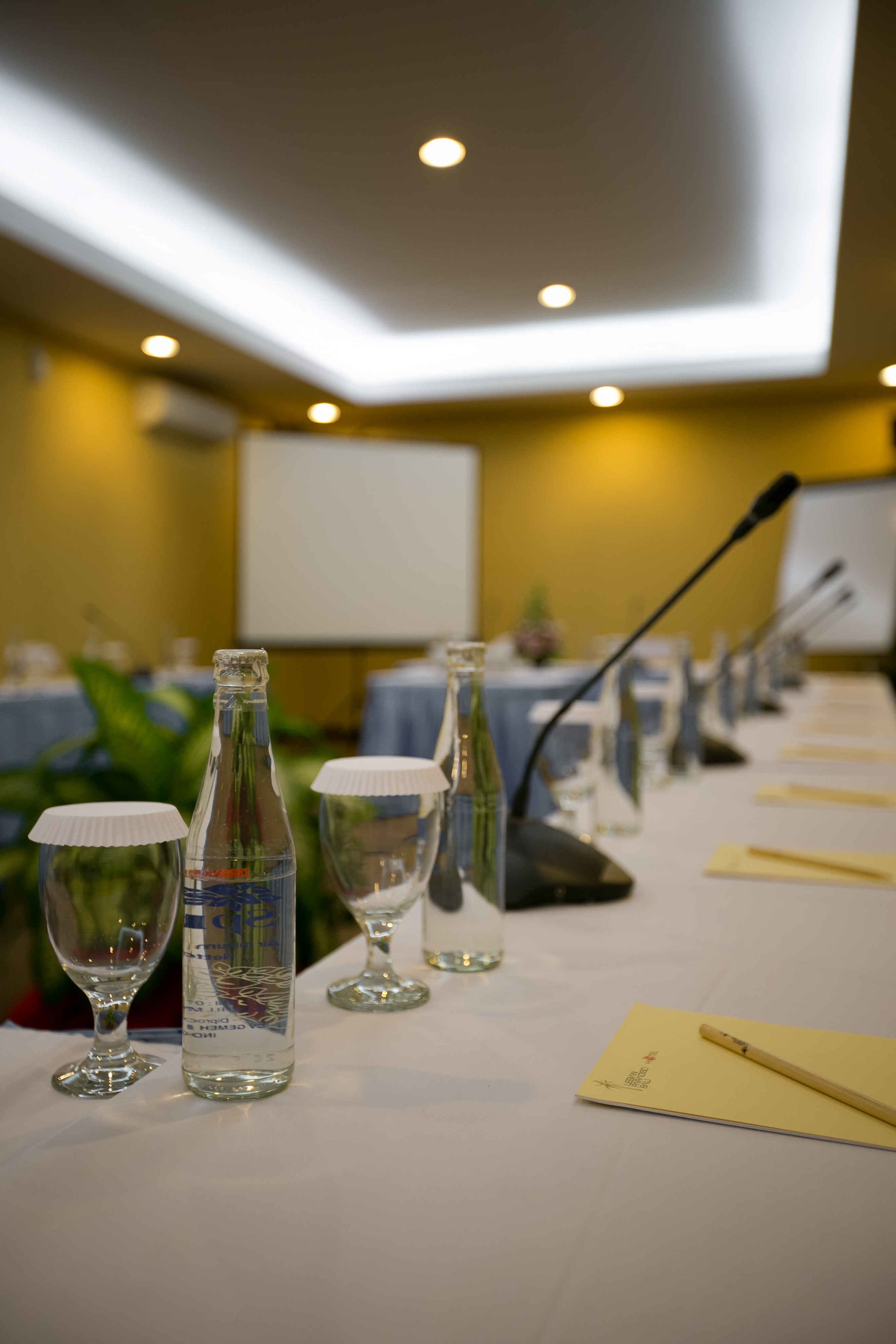A conference table with microphones, water bottles, and wine glasses.