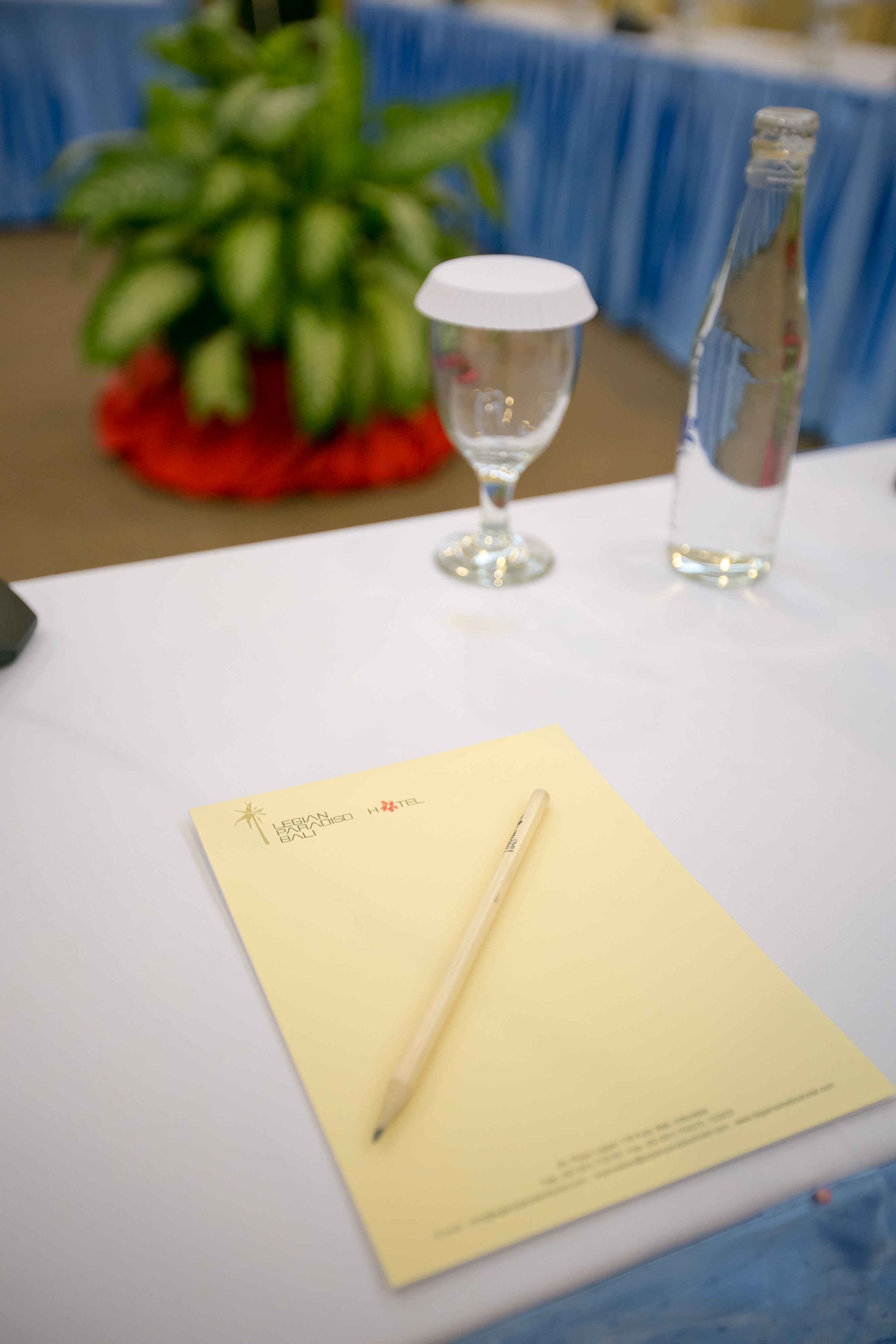 A table with a yellow note, a pen, a glass, and a bottle.