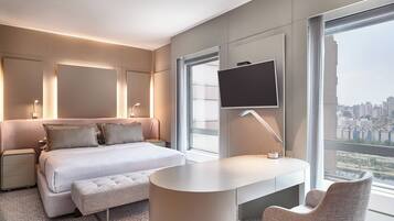 Una habitación de hotel moderna con una cama grande, un escritorio, una silla y un televisor montado en la pared.