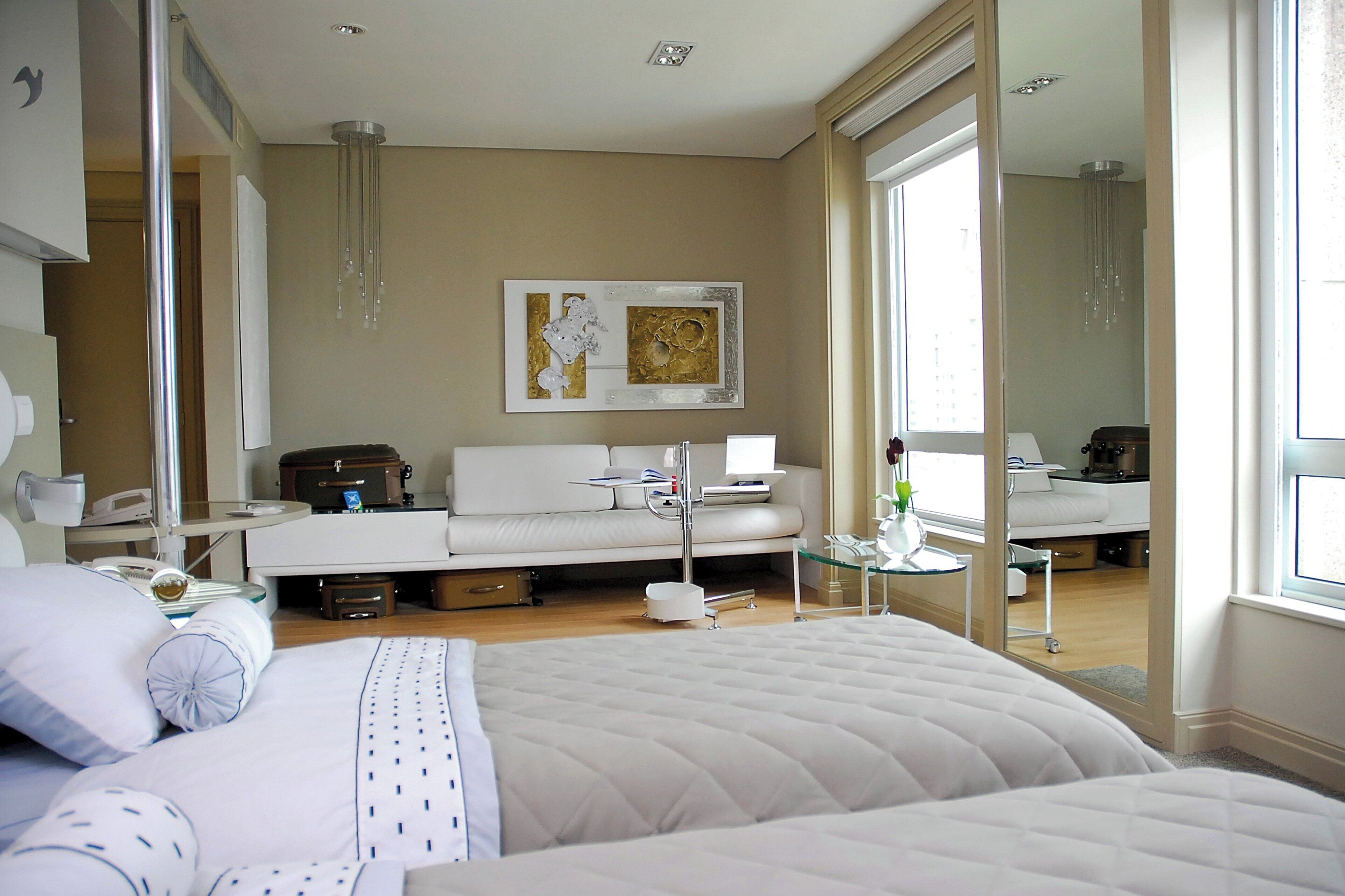 Ein modernes Hotelzimmer mit einem großen Bett, einer Couch, einem Schreibtisch und einem Spiegel.