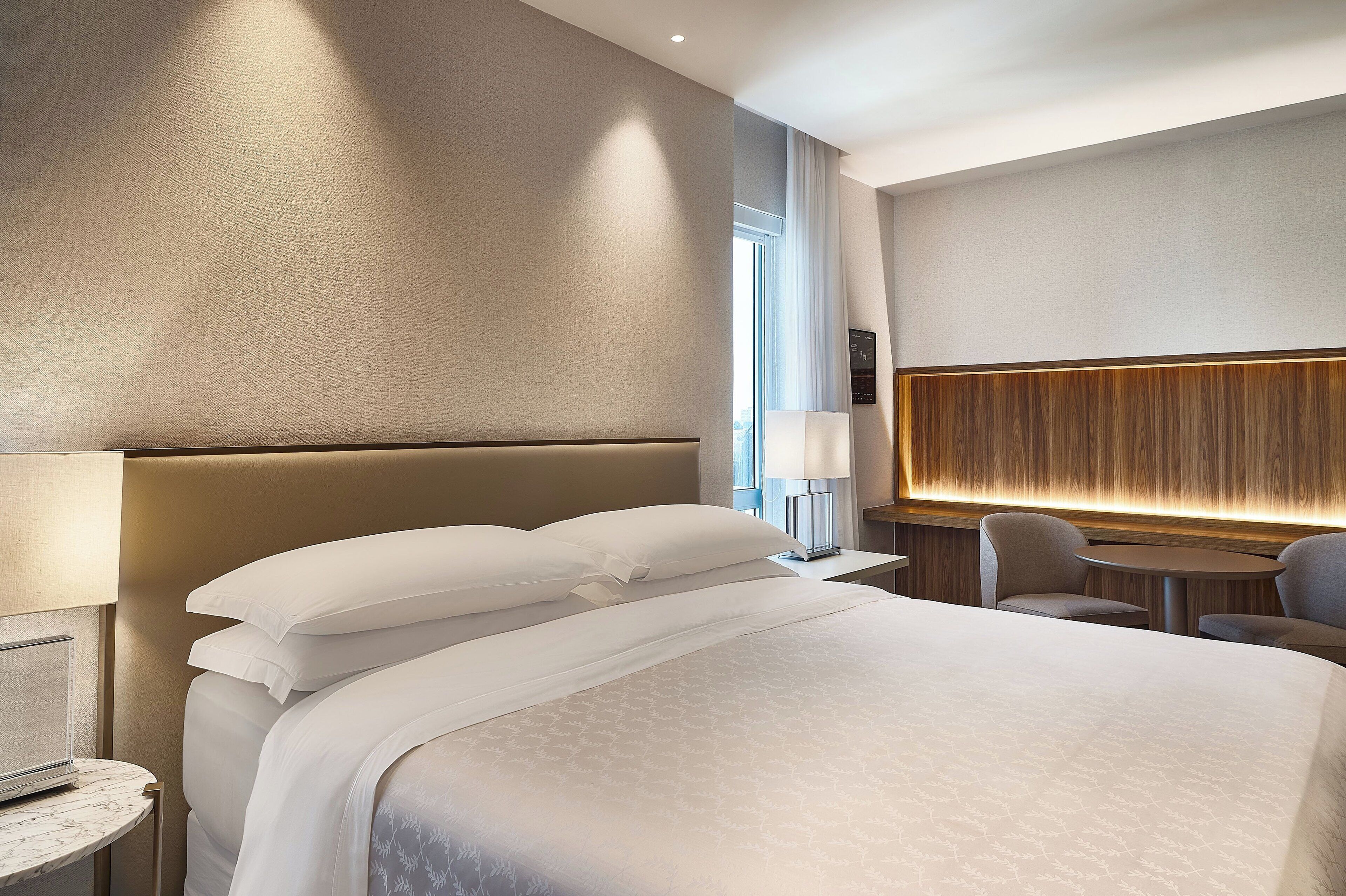 A modern hotel room with a large bed, a round table, and a seating area.