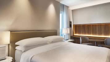 A modern hotel room with a large bed, a round table, and a seating area.