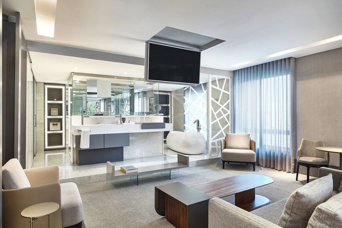 A modern living room with a sofa, coffee table, and a TV mounted on the ceiling.