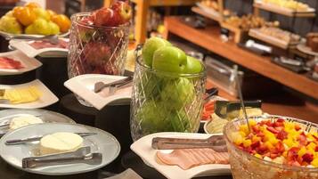 Un buffet proposant une variété de plats, notamment des fruits, des fromages et des viandes.
