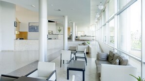 A spacious lobby with a reception desk, seating area, and large windows providing natural light. - TRYP by Wyndham Porto Expo Hotel (Matosinhos)