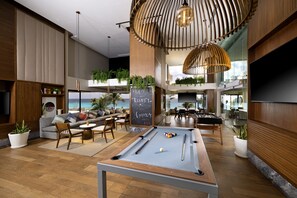 Relax in a stylish lounge area with a pool table, comfortable seating, and potted plants.