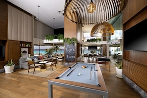 Relax in a stylish lounge area with a pool table, comfortable seating, and potted plants.