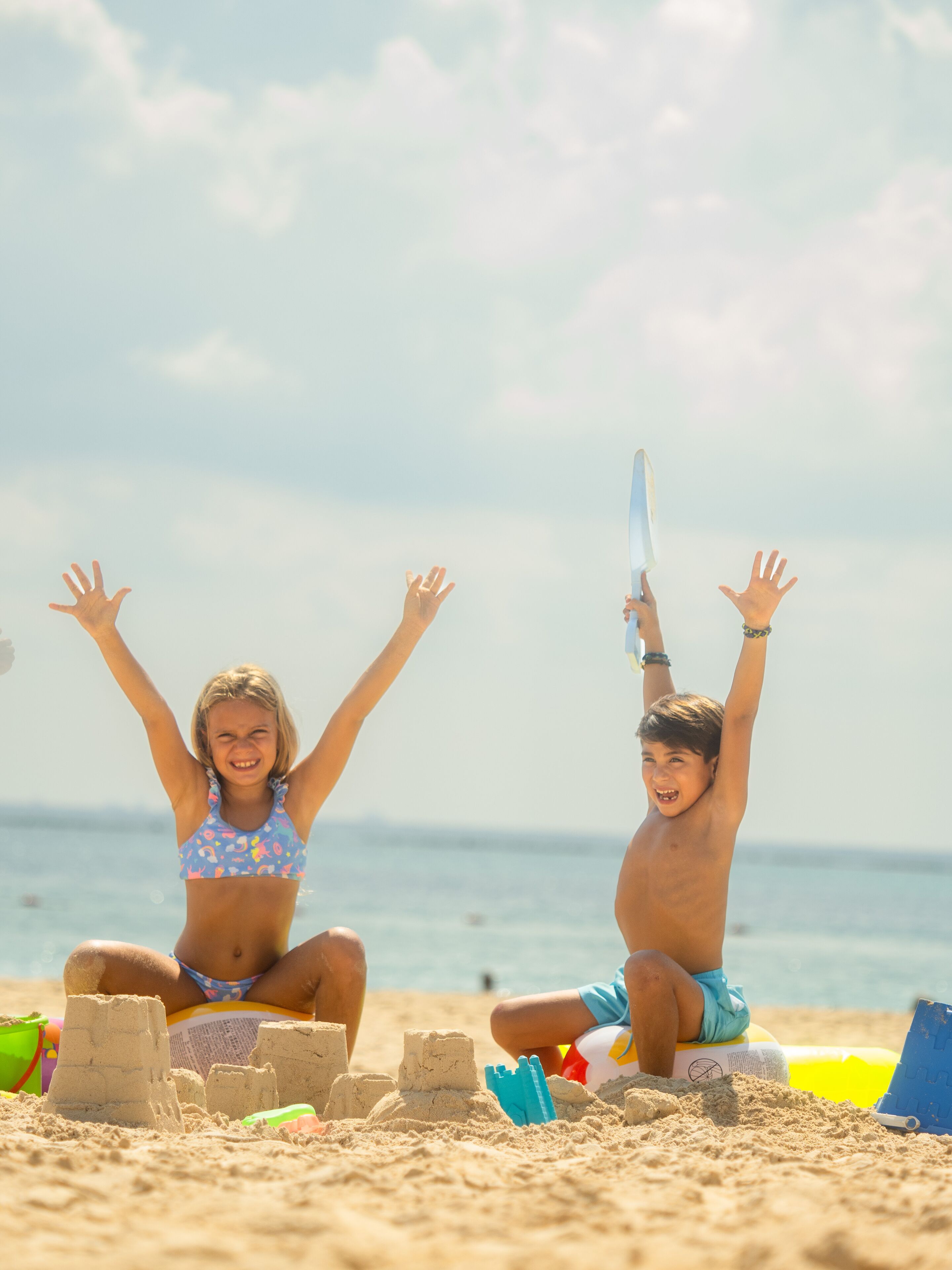 Two children playing with sand on a beach.