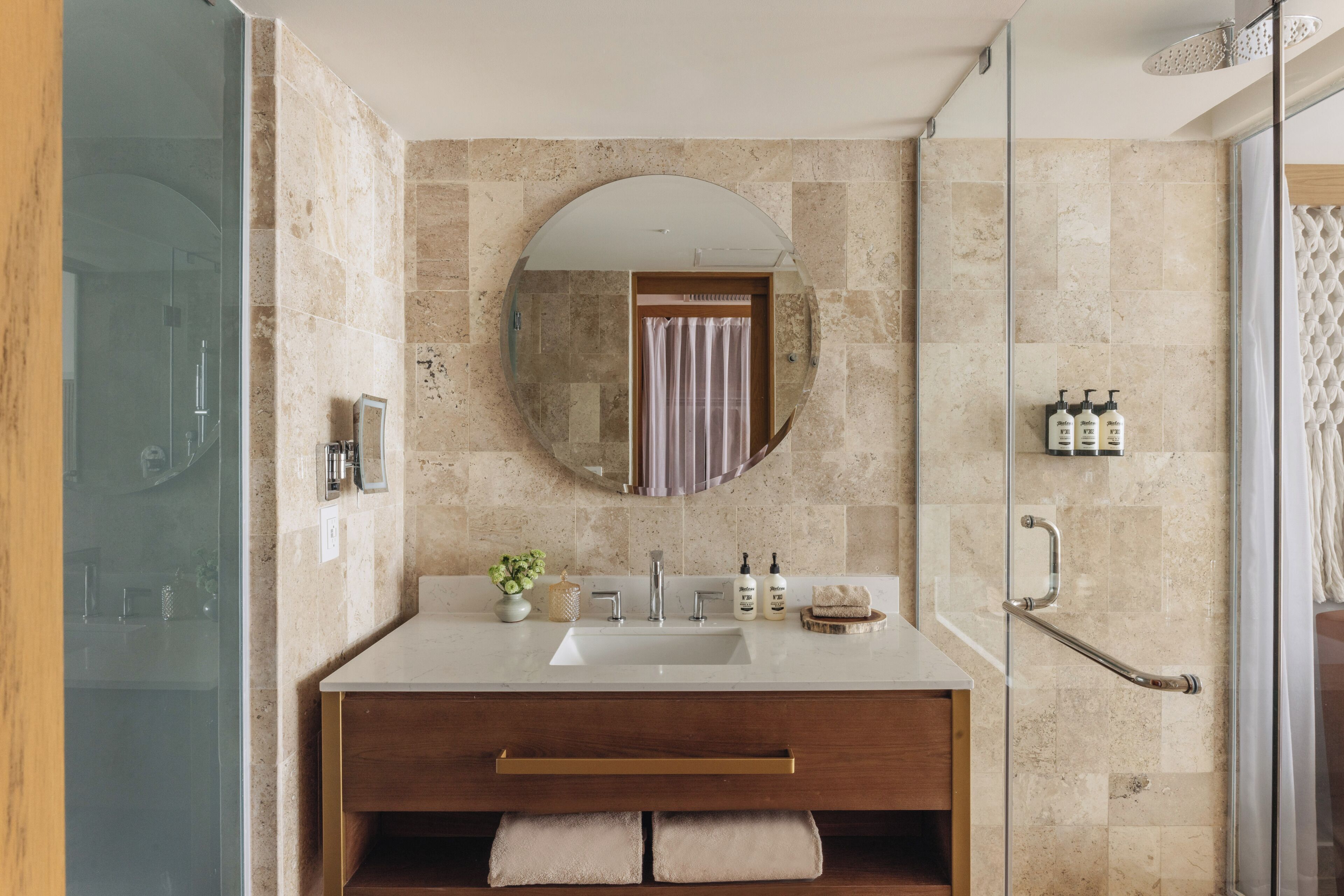 A bathroom with a glass shower enclosure, a vanity with a sink, a mirror, and a towel rack.