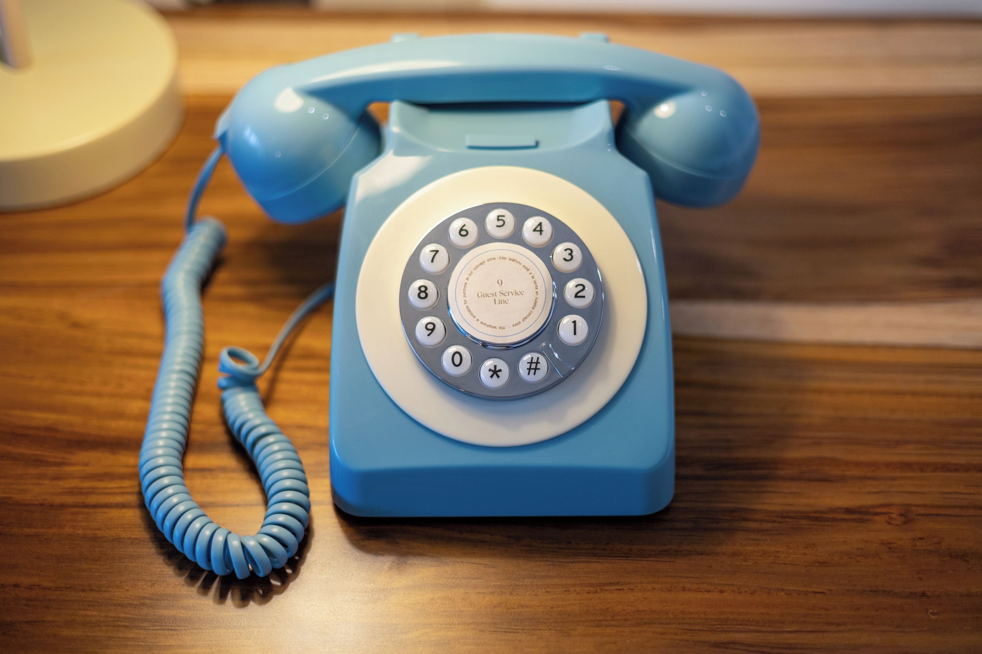 A blue rotary dial telephone on a wooden surface.