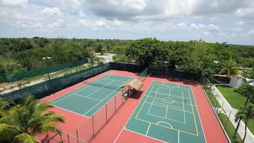 Ein Tennisplatz mit Netz, umgeben von einem grünen Zaun und in der Nähe Palmen.
