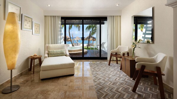 A spacious room with a large window offering a view of a beach and pool, a comfortable seating area with a sofa and chairs, and a small table with a vase of flowers. - Zel Cozumel (Cozumel)