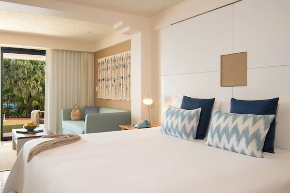 A hotel room with a large bed, a seating area with a view, and a window with curtains. - Zel Cozumel (Cozumel)