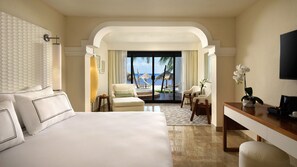 A hotel room with a large bed, a desk, a chair, and a view of the beach. - Zel Cozumel (Cozumel)