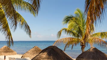 På stranden, hvidt sand, liggestole, parasoller