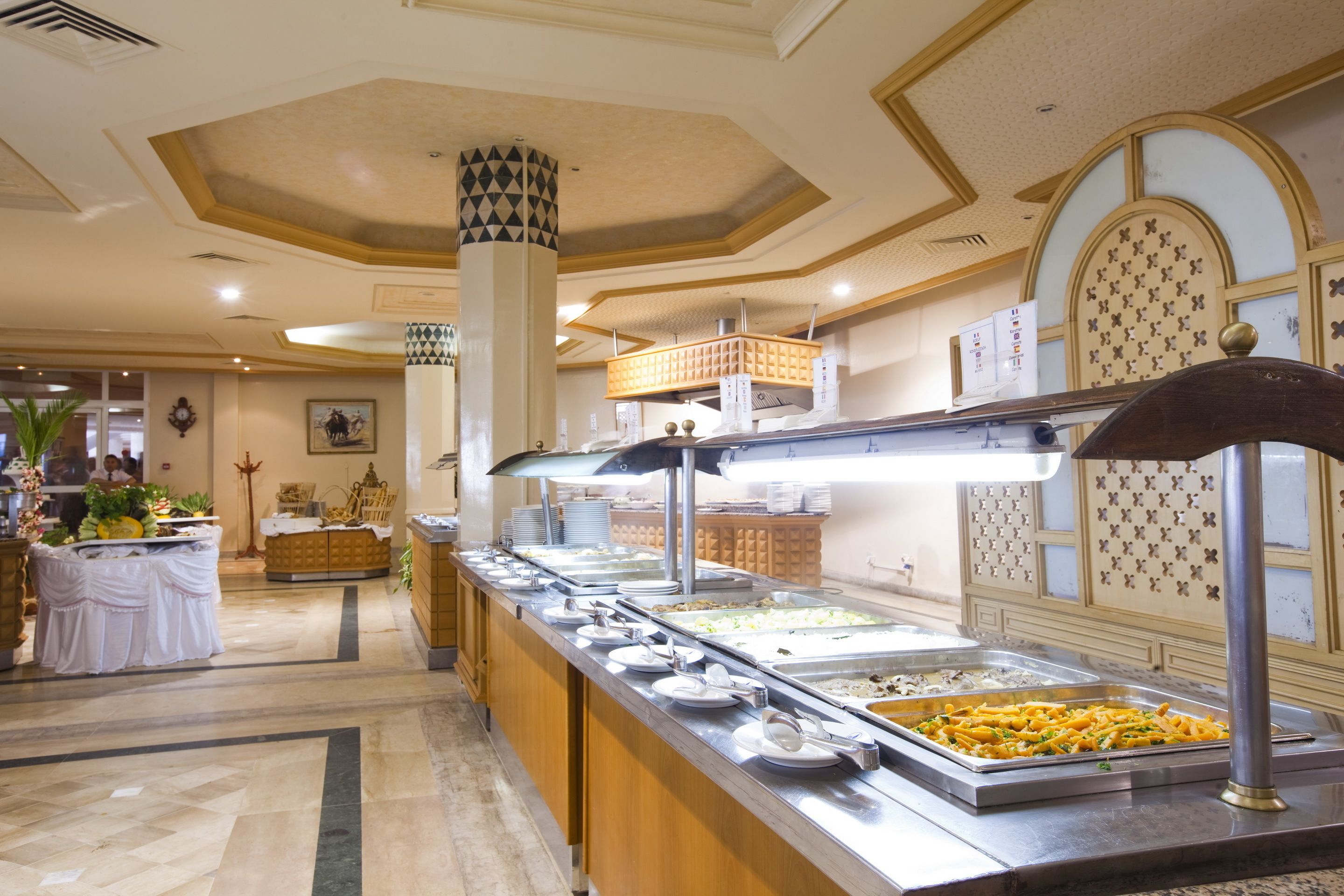 Un espace buffet comprenant plusieurs présentoirs de nourriture et un mur décoratif orné d’un motif géométrique.