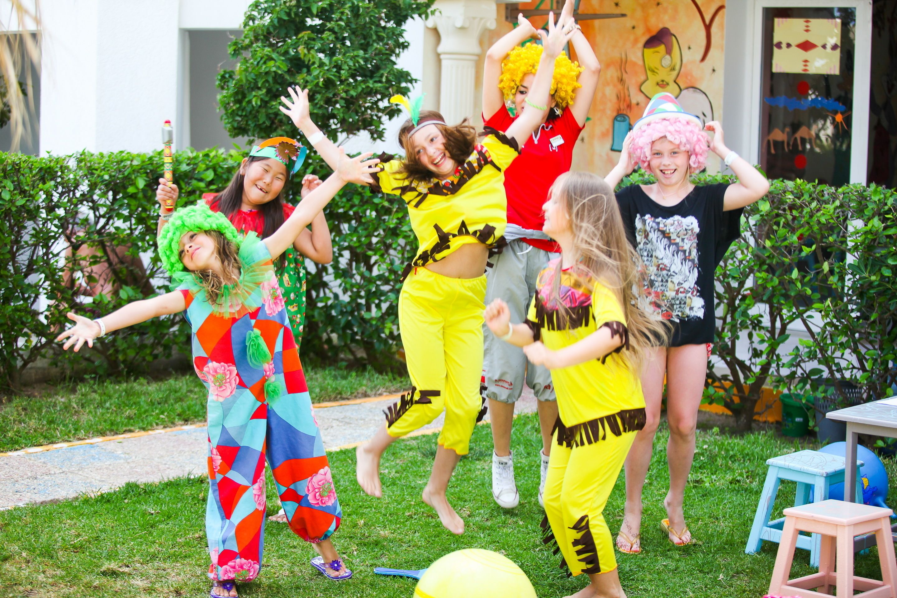 A group of people in colorful costumes jumping outdoors.