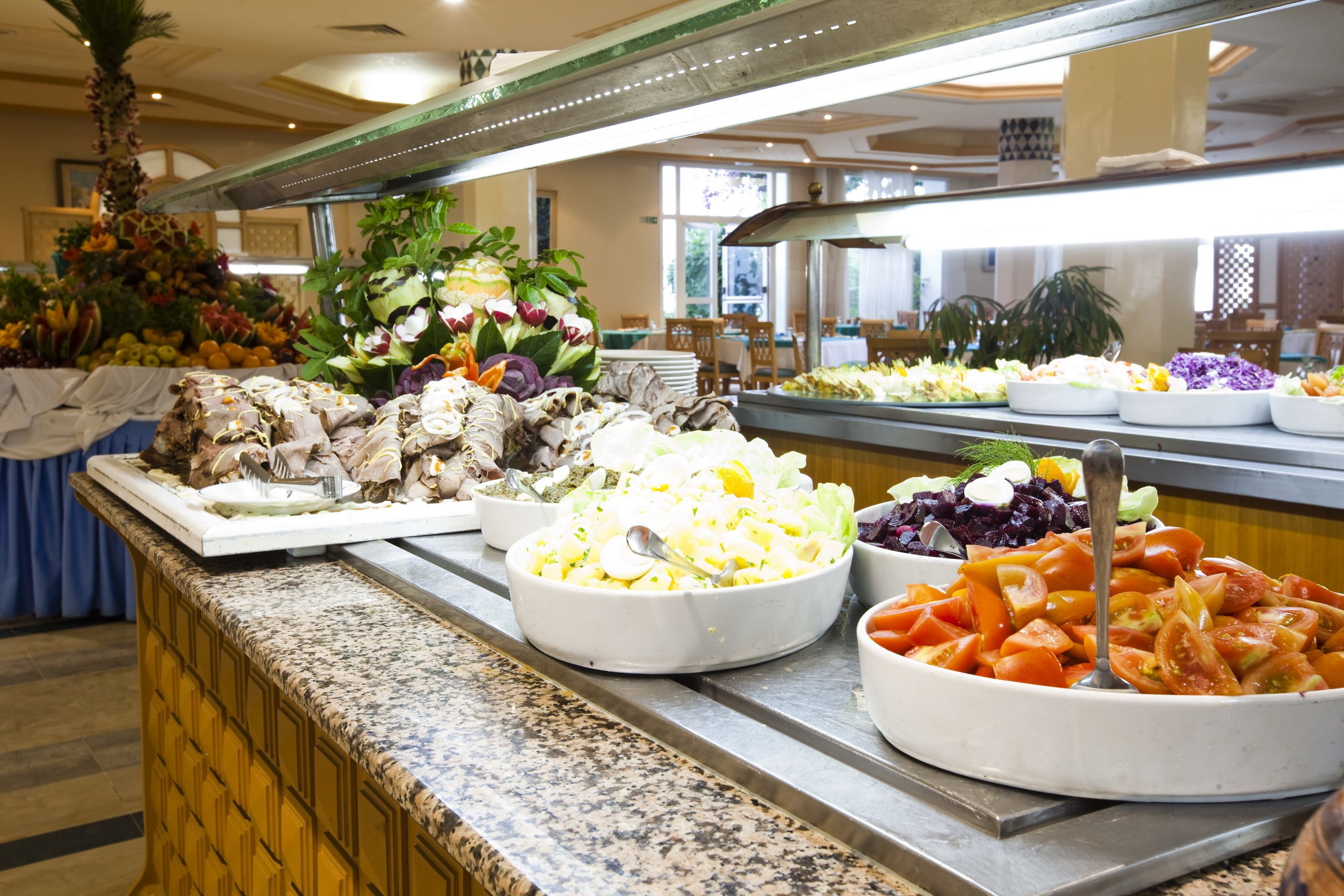 A buffet with various dishes including salads, fruits, and vegetables.