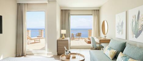 Une chambre d’hôtel comprenant un lit, un canapé, un bureau et un balcon avec vue sur la mer.